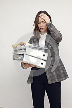 Frustrated and confused female worker and business woman holding a pile of paperwork while feeling aheadache. Looking stressed iso