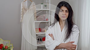 Frustrated depressed Middle Eastern beautiful bride looking back at wedding dress turning to camera shaking head no