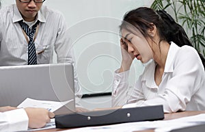 Frustrated depressed young Asian business woman with hands on face suffering from severe problem between meeting in office.