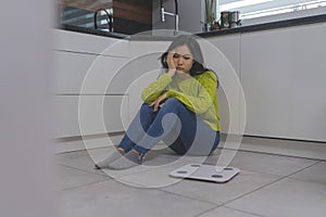 Frustrated dieting young asian woman sitting on the flor with weight scale in front. Weight loss and mental health