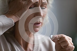 Frustrated elderly 60s lady holding dose of pills