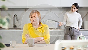 Frustrated elderly mother having tense conversation with her daughter