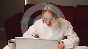 Frustrated exhausted businesswoman working on laptop at home office, young woman upset stressed typing at the laptop