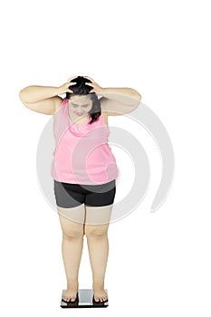 Frustrated fat woman stands on scale