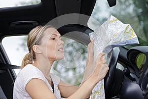 Frustrated female car driver looking at map