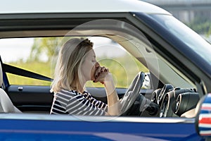 Frustrated female driver sit inside car with chin on hands scared to drive after vehicle accident