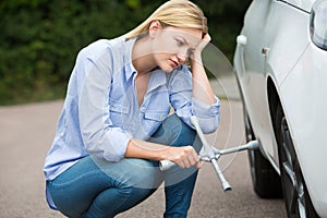 Frustrated Female Driver With Tire Iron Trying To Change Wheel