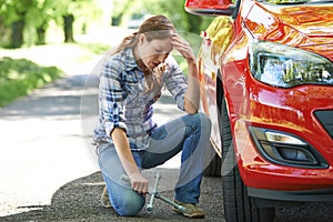 Frustrated Female Driver With Tyre Iron Trying To Change Wheel