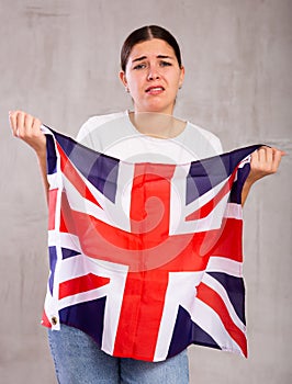 Irritated young woman with Britannic flag. Isolated on gray background photo