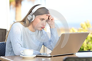 Frustrated girl checking laptop in a coffee shop terrace