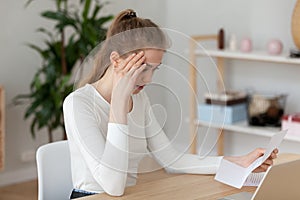 Frustrated girl read unpleasant letter sitting at the desk