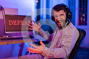 Frustrated guy at computer with 'defeat' sign