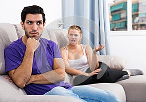 Frustrated guy on couch with dissatisfied girlfriend