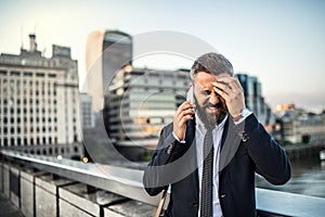 Frustrated hipster businessman with smartphone in the city, making a phone call.