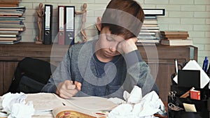 Frustrated little boy tired of his homework crumples his paper