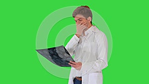 Frustrated male doctor examining computed tomography scan of brain on a Green Screen, Chroma Key.