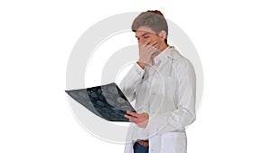 Frustrated male doctor examining computed tomography scan of brain on white background.