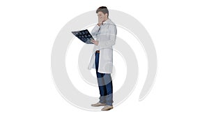 Frustrated male doctor examining computed tomography scan of brain on white background.