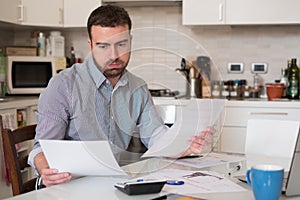 Frustrated man calculating bills and taxes expenses