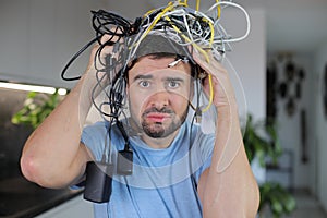 Frustrated man holding many tangled wires