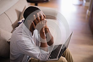 Frustrated man with laptop sitting at home