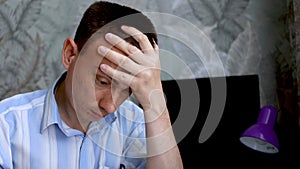 Frustrated man sitting at desk with paper bills. Bankruptcy concept