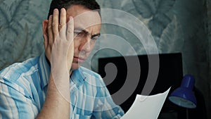 Frustrated man sitting at desk with paper bills. Bankruptcy concept