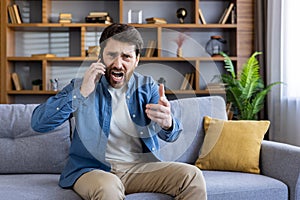 Frustrated man talking on phone while sitting on couch