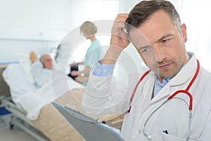 Frustrated mature doctor scratching head in patients room