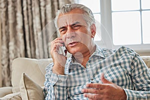 Frustrated Mature Man Receiving Unwanted Telephone Call At Home