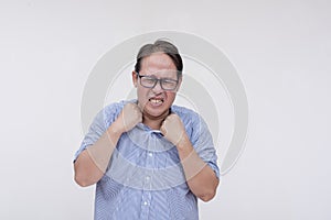 A frustrated middle aged asian man grabbing his collar feeling the intense stress. Isolated on a white backdrop