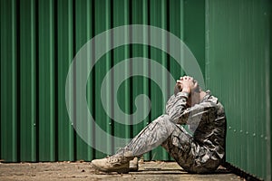 Frustrated military soldier sitting with hands on head