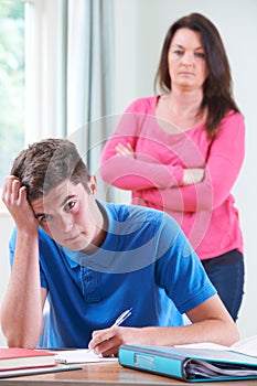 Frustrated Mother Watching Teenage Son Doing Homework