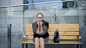 Frustrated office employee sitting on bench, tired after stressful meeting