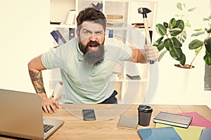 Frustrated office worker holding hammer poised ready to smash. Office life makes him crazy. Businessman with beard and