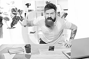 Frustrated office worker holding hammer poised ready to smash. Office life makes him crazy. Businessman with beard and