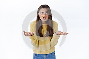 Frustrated and pissed-off angry tensed young woman cursing for bad luck or failure, shrugging with hands spread sideways