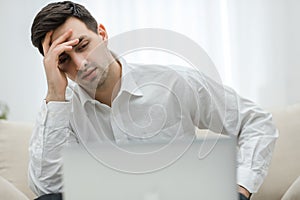 Frustrated with problems young business man working on laptop computer at home.