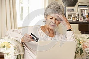 Frustrated Retired Senior Woman Sitting On Sofa At Home Using Laptop