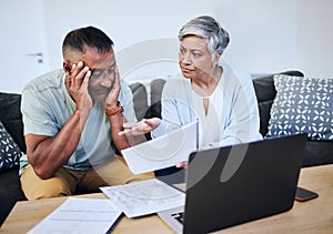 Frustrated senior couple, documents and laptop in debt, financial crisis or struggle on sofa at home. Upset elderly man