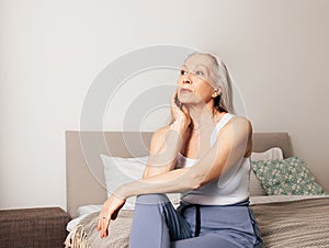 Frustrated senior female sitting on a bed