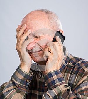 Frustrated senior man in shirt talking on the mobile phone