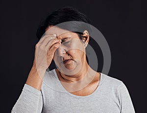 Frustrated senior woman, headache and anxiety in studio for depression, debt and confused on black background. Face of