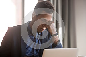 Frustrated stressed black businessman feel eye strain headache at work