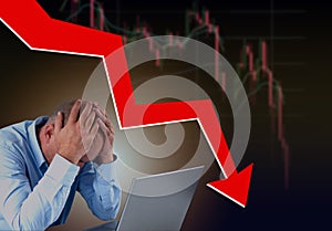 Frustrated stressed failed business man sitting with laptop with financial market chart graphic going down. Poor economy concept.