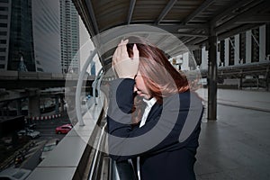 Frustrated stressed young Asian business woman covering face with hands at urban city background.