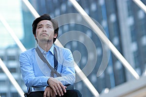 Frustrated stressed young Asian businessman feeling exhausted and headache against job at urban building with copy space backgroun