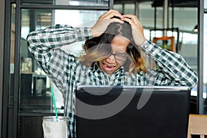 Frustrated stressed young Asian man in casual clothes feeling stress in office.