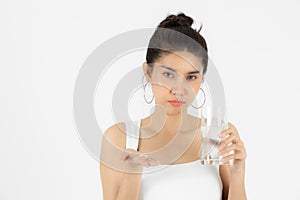 Frustrated stressed young Asian woman holding pills over green  background. Medicine and health care concept