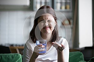 Frustrated stressed young woman grimacing afraid of taking pill